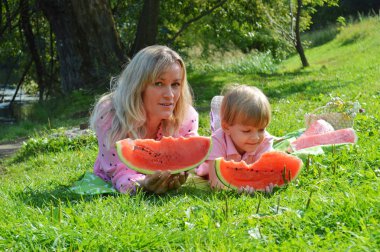 Nehir kıyısında annesiyle birlikte karpuz yiyen küçük bir çocuk..