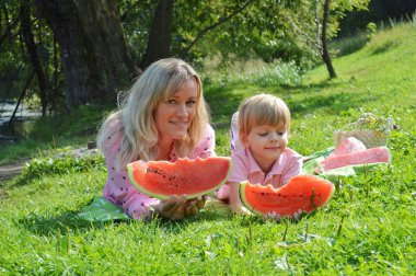 Nehir kıyısında annesiyle birlikte karpuz yiyen küçük bir çocuk..