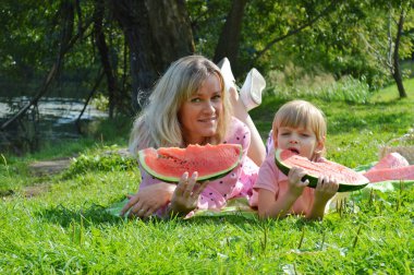 Nehir kıyısında annesiyle birlikte karpuz yiyen küçük bir çocuk..