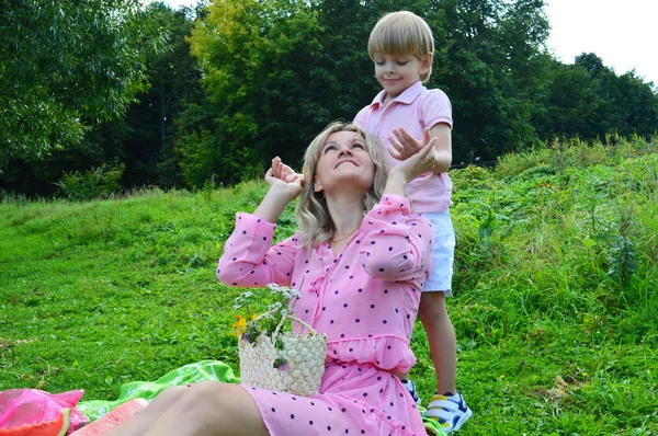 Маленький хлопчик на траві з матір'ю в літньому парку . — стокове фото
