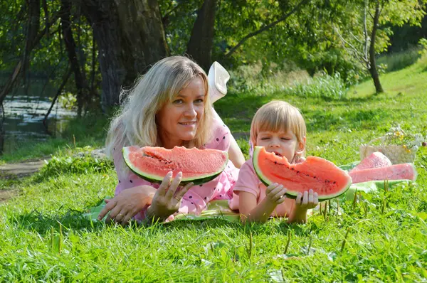 Nehir kıyısında annesiyle birlikte karpuz yiyen küçük bir çocuk..
