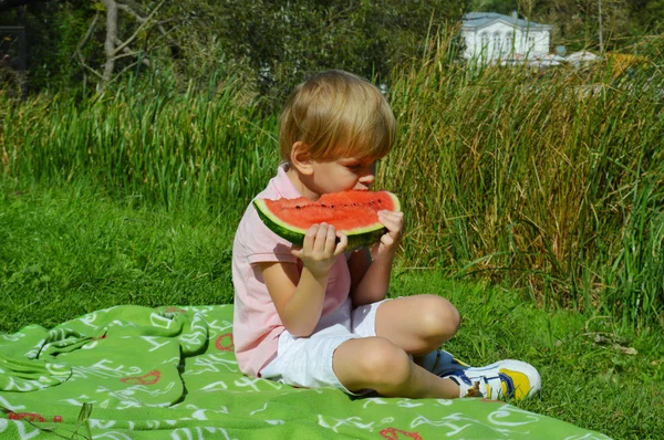 Menino junto ao rio comendo melancia . — Fotografia de Stock