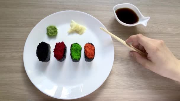 Bere sushi s dřevěnými tyčinkami a máčí se v sójové omáčce — Stock video