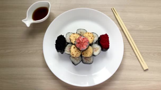 Rolos e sushi dobrados na forma de um bolo em uma placa branca — Vídeo de Stock