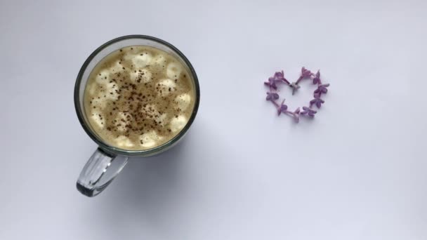 Kawa z piankami i cynamonem. Wysadza kwiaty bzu w kształcie serca — Wideo stockowe