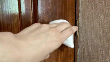 Kadın, antiseptik dezenfektanla kapı kolunu temizliyor..