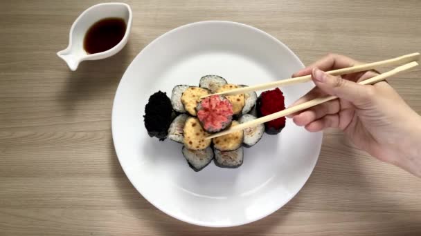 Sushi plié sous forme de gâteau sur une plaque blanche. Il prend des baguettes en bois de sushi — Video