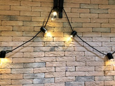 Duvarın arkasında lamba çelengi, yakın plan. Tuğla bir duvarın arka planında bir çelenk üzerindeki ampuller