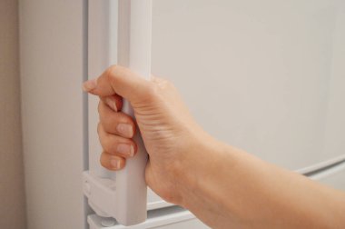 Kadın eli beyaz buzdolabının kapısını açar..