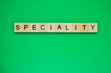 Sözcük spesyalitesi. Ahşap bloklar ve yeşil arka planda harfler. Yeşil yüzeyde harfleri olan tahta blokların üst görünümü