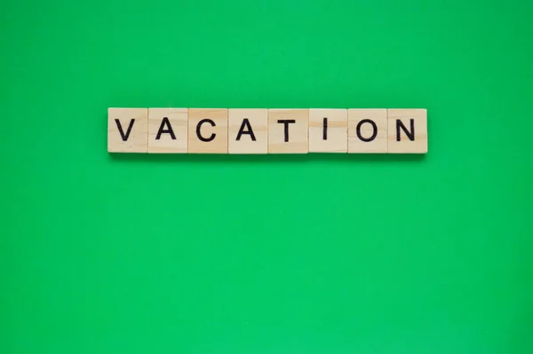 休暇の言葉だ 緑の背景の上にレタリングと木製のブロック 緑の表面に文字を持つ木製のブロックのトップビュー — ストック写真