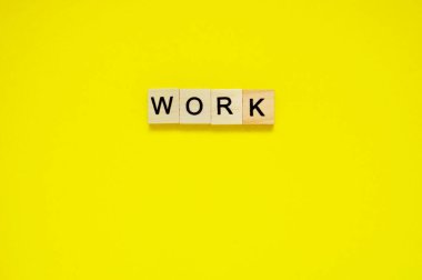 Kelime oyunu. Sarı arka planda harfleri olan tahta bloklar. Sarı yüzeyde harfleri olan tahta blokların üst görünümü