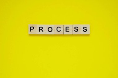 Kelime süreci. Sarı arka planda harfleri olan tahta bloklar. Sarı yüzeyde harfleri olan tahta blokların üst görünümü