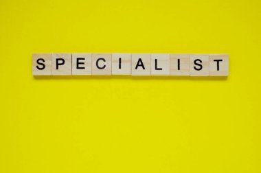 Kelime uzmanı. Sarı arka planda harfleri olan tahta bloklar. Sarı yüzeyde harfleri olan tahta blokların üst görünümü