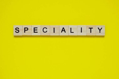 Kelime uzmanlığı. Sarı arka planda harfleri olan tahta bloklar. Sarı yüzeyde harfleri olan tahta blokların üst görünümü