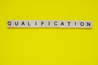 Kelime yeterliliği. Sarı arka planda harfleri olan tahta bloklar. Sarı yüzeyde harfleri olan tahta blokların üst görünümü