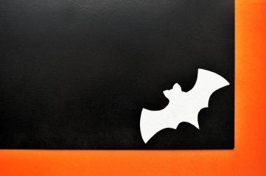 Beyaz kağıt yarasa turuncu-siyah arkaplanda yatıyor