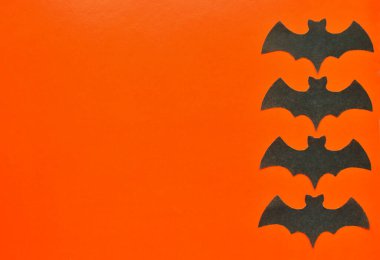 Siyah kağıt yarasalar turuncu arka planda yatar.
