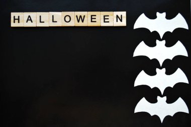 Beyaz kağıt yarasalar siyah arka planda yatar. Tahta blokların cadılar bayramı sözcüğü.