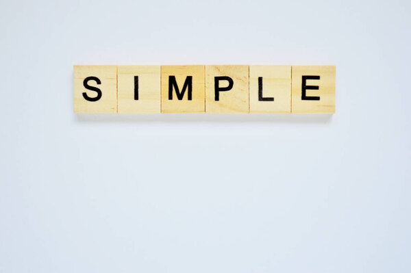 Word simple. Wooden blocks with lettering on top of white background. Top view of wooden blocks with letters on white surface