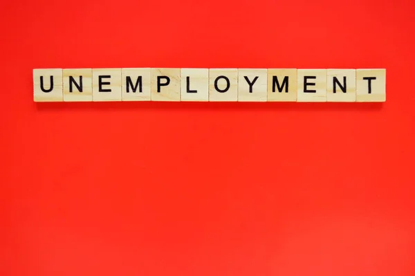 失業という言葉 赤い背景の上に文字が書かれた木製のブロック 赤い表面に文字を持つ木製のブロックのトップビュー — ストック写真