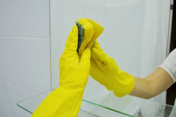 ゴム製の黄色の手袋で手をスポンジでミラーを洗う — ストック写真