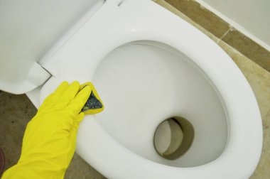 Kauçuk sarısı bir eldiven ile tuvaleti süngerle yıkar.