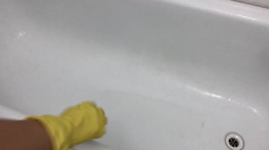 Lastik sarısı bir eldiven banyoyu süngerle yıkar..