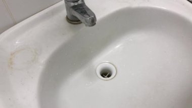 Lastik sarısı eldivendeki bir el deterjanı tutar ve lavaboyu yıkar..