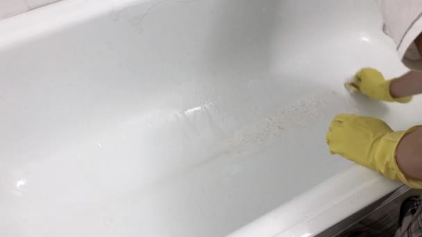 Kéz egy gumi sárga kesztyű mossa a fürdőt egy szivaccsal. — Stock videók