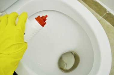 Kauçuk sarısı bir eldiven verin. Tuvaletin arka planında deterjan olsun.