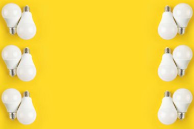 Sarı arka planda beyaz mat renginde ampuller. Elektrik kavramı. Minimalist kavram, parlak fikir, izole lamba. Uzayı kopyala Yukarıdan manzara. Düzgünce.