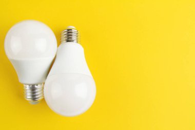 Sarı arka planda beyaz mat renginde iki ampul. Elektrik kavramı. Minimalist kavram, parlak fikir, izole lamba. Uzayı kopyala Yukarıdan manzara. Düzgünce.