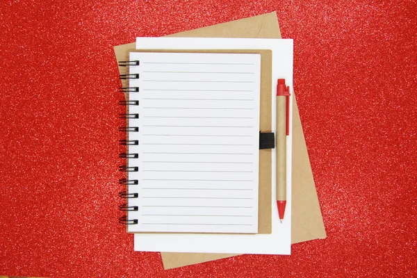 Not Defteri 'nde ofis aksesuarlarıyla yeni yıl hedefi, planı, aksiyon metni. İş motivasyonu, ilham kavramları. Not defteri ve kalem, parlak kırmızı arka planda bir zarf. Dümdüz. Yukarıdan görünüşü.