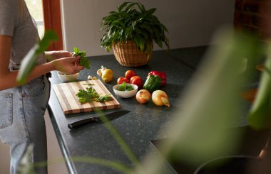 İnternette tarifi takip eden isimsiz bir kadın dizüstü bilgisayarla yemek hazırlıyor.