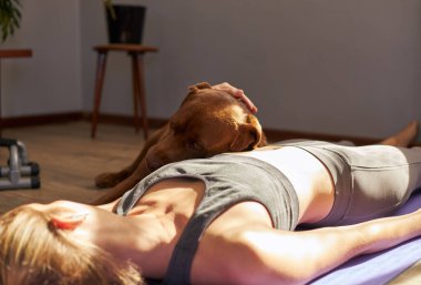 Genç bayan sabah güneşinde köpekle antrenmandan sonra mindere uzanıyor..