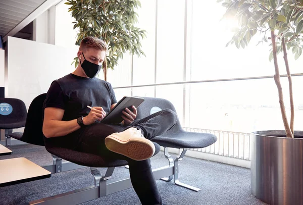 Masculino Esperando Aeroporto Vazio Usando Máscara Protetora Usando Tecnologia — Fotografia de Stock