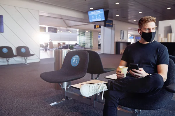 Masculino Esperando Aeroporto Vazio Usando Máscara Protetora Usando Tecnologia — Fotografia de Stock