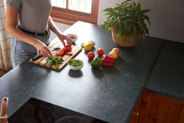 Young woman preparing vegetarian dinner in a kitchen clipart