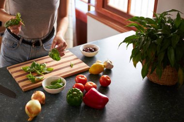 Genç bir kadın mutfakta vejetaryen yemeği hazırlıyor.