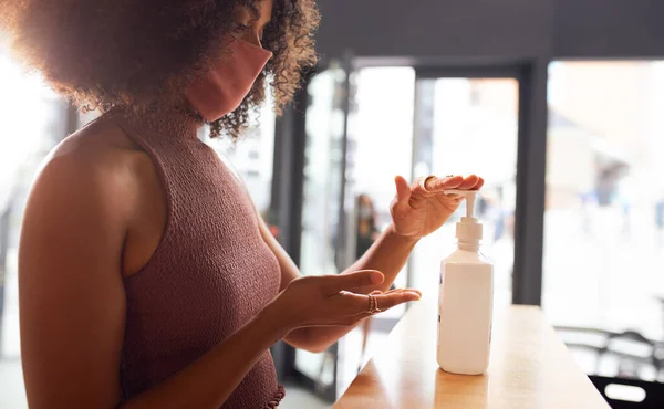 Businesswoman using hand sanitizer at reception before entering office.