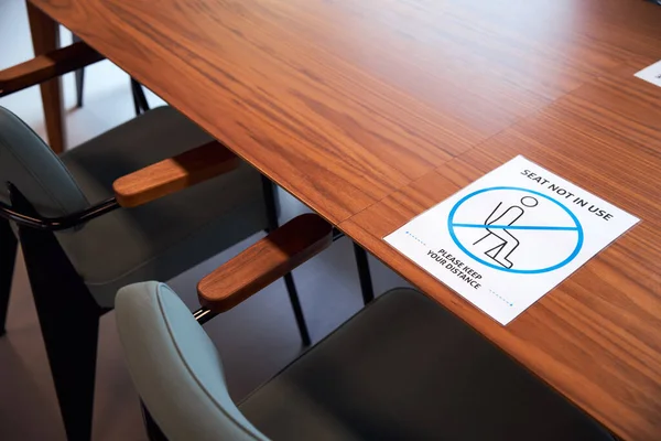 Social distancing sign in office on meeting room table.