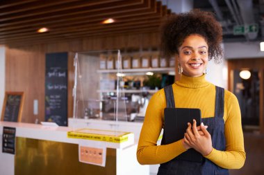 Sağlık Salgını sırasında dijital tablet kullanan Maskeli Kadın İşletme Sahibinin Portresi