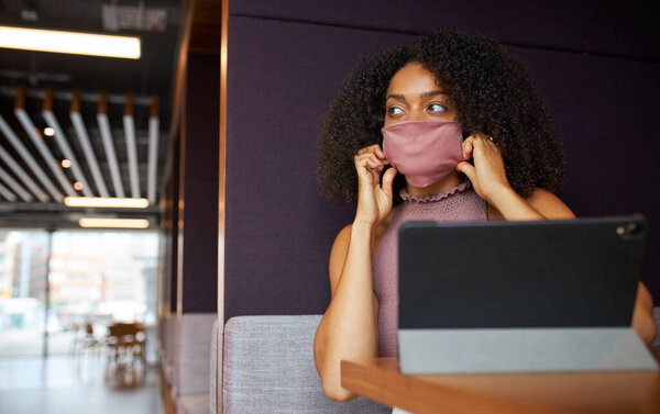 Деловая женщина в маске, работающая в социально отдаленной кабинке во время пандемии здоровья