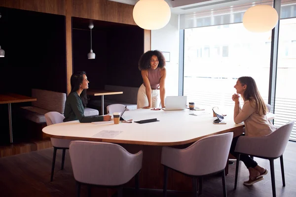 Three Businesswomen Having Socially Distanced Meeting In Office During Health Pandemic