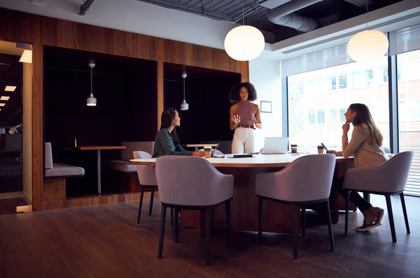 Three Businesswomen Having Socially Distanced Meeting In Office During Health Pandemic