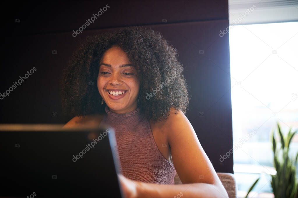 Portrait Of Businesswoman Sitting At Meeting Table Working On Laptop In Modern Open Plan Office