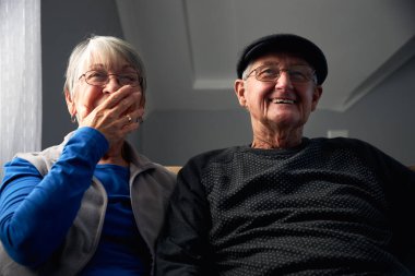 Son sınıf çifti koltukta oturup birlikte televizyon seyrediyor.