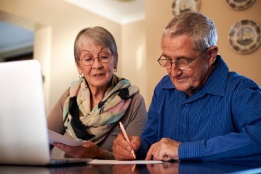 Senior Couple At Home Checking Personal Finances On Laptop clipart