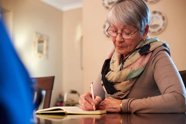 Mulher Sênior Casa Sentada Mesa Escrevendo Caderno Jornal — Fotografia de Stock